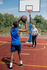 Fototapeta premium multiracial elderly men playing basketball together on playground on summer day