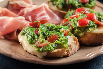 Bruschetta with fresh pesto, mozzarella and cherry tomatoes on a plate