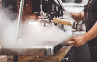 Fototapeta na wymiar Coffee machine in steam, barista preparing coffee at cafe
