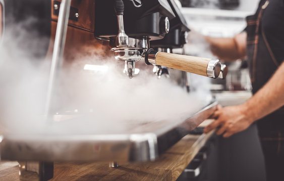 Coffee machine in steam, barista preparing coffee at cafe