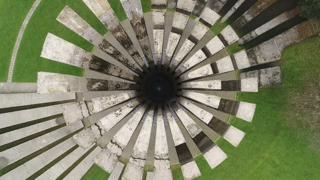 Descending drone shot of cylinder shaped concrete monument on peak of Kozara mountains, commemorating partisan fighters who died in battle against Nazi Germany, in today's Bosnia and Herzegovina
