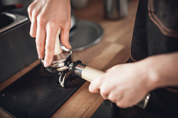 Barista in apron with piston and tamper preparing coffee at cafe