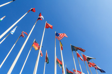 Bottom view of a rows of flags of different countries of the world, flutters in the wind, against a...