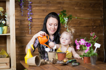 woman is teaching her daughter to plant flowers