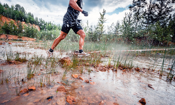 Cross country trail runner moving through water on rural road