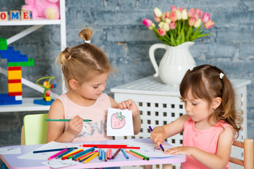 Two little beautiful girls draw with colorful pencils
