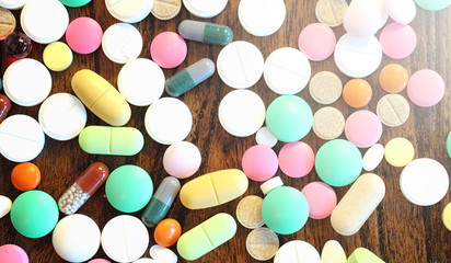 Drugs and coins in a glass jar on a wooden floor. Pocket savings