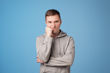 Studio shot of angry man holding arms near face, having skeptical and dissatisfied look standing