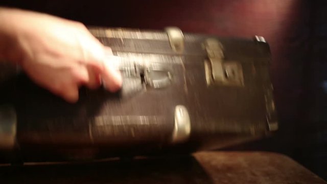 Close up shot of a man closing old suitcase.