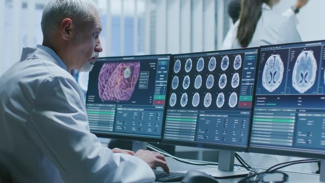Senior Medical Research Scientist Working with Brain Scans on His Personal Computer. Modern Laboratory Working on Neurophysiology, Science,  Neuropharmacology. Shot on RED EPIC-W 8K.