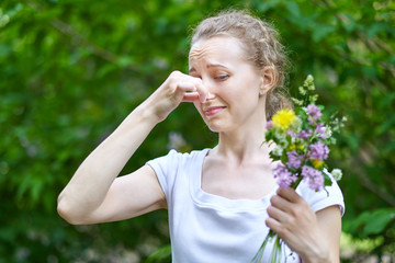 Fototapeta premium Allergy. Woman squeezed her nose with hand, so as not to sneeze from the pollen of flowers