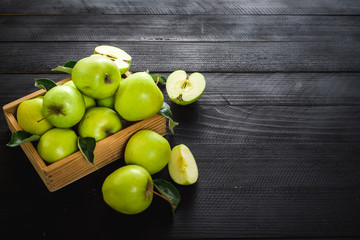 Tasty and fresh green apples in wooden box on the black wooden background. Top view. Copy space