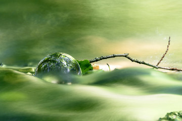 Glass orb in a peaceful forest shining in a river