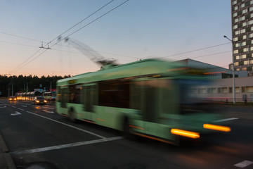 Obraz na płótnie Canvas Movement of a blurred trolleybus at dusk along the street.