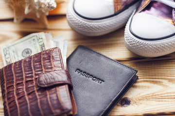 Outfit and accessories for travel. Camera, passports, wallet with money, sneakers and jeans on the wooden background. Laptop and notebook for planning. Travel, lifestyle, fashion and vacation concept