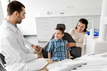 medicine, dentistry and healthcare concept - mother and son visiting dentist at dental clinic