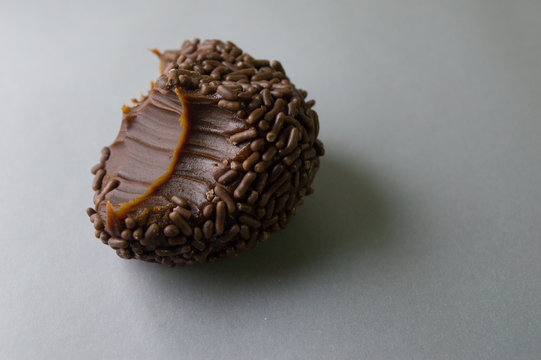 Grande doce brasileiro brigadeiro mordido isolado em fundo cinza