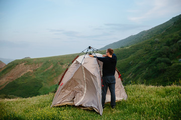 installing a camping tent with mountains in the background