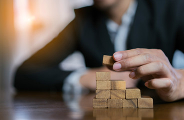 Businessman planing and strategy putting wooden blocks risk or success project hands control stack...