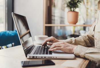 Male hands working on laptop computer in the office, online shopping, business and technology concept