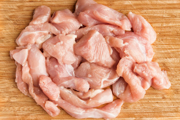 Fresh chicken fillet pieces on a wooden cutting board, top view