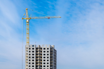 Tower cranes and unfinished multi-storey high near buildings under construction site in the morning