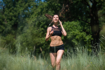 Naklejka na ściany i meble Girl athlete running in the woods, doing sports outdoors