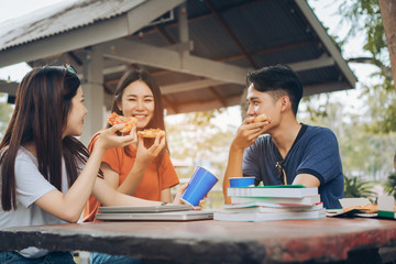 Asian young group together eating pizza in breaking time having fun and enjoy party italian food slice,drinking carbonated with cheese delicious.
