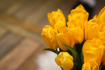 A bouquet of yellow tulips in a vase in the interior of a retro
