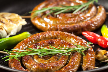 Grilled spiral sausages in a pan - obrazy, fototapety, plakaty