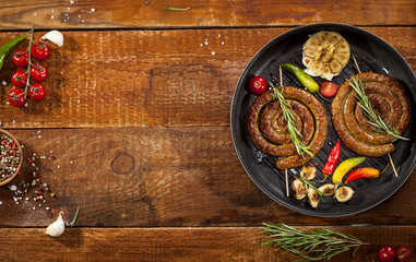 Grilled spiral sausages in a pan on wooden background