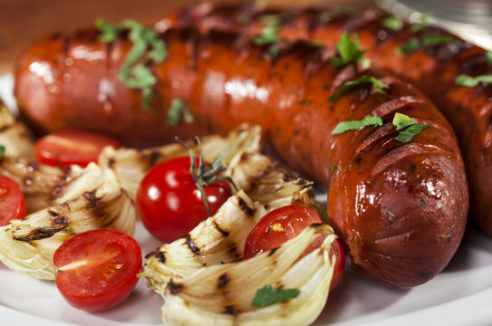 Grilled sausages on a white plate and wooden background