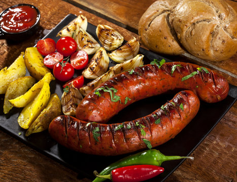 Grilled sausages in a plate on wooden background