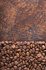 Black roasted coffee grains lie on a copper table.