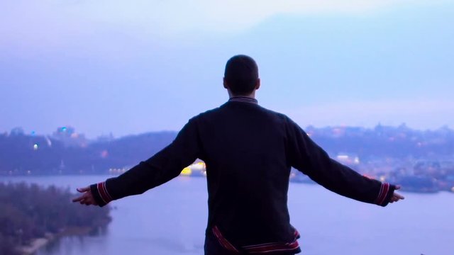 Man raises hands to sky, feels strength and self-confidence to conquer world