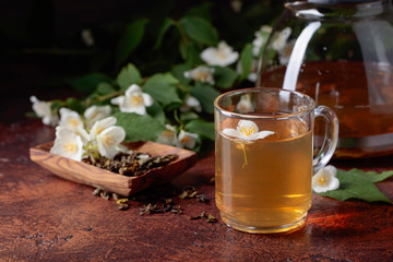 Green tea with jasmine in cup and teapot .