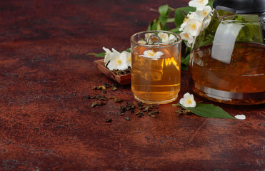Green tea with jasmine in cup and teapot on old copper table.
