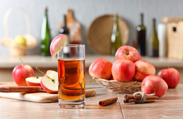 Glass of apple juice , apples and cinnamon sticks .