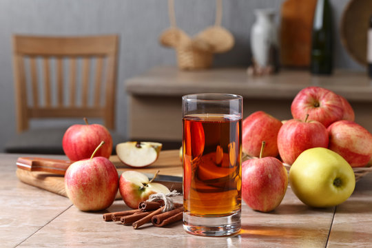 Glass of apple juice , apples and cinnamon sticks .