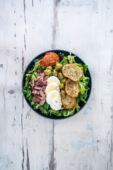Salad with speck ham and egg, tomatoes