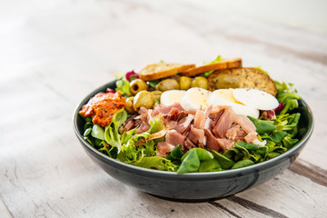 Salad with speck ham and egg, tomatoes