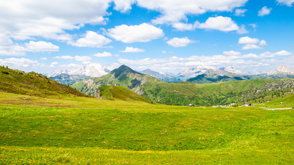 Naklejka premium Landscape of Dolomites with green meadows, blue sky, white clouds and rocky mountains.