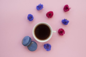 Cup of coffee and macaroons on pink background.