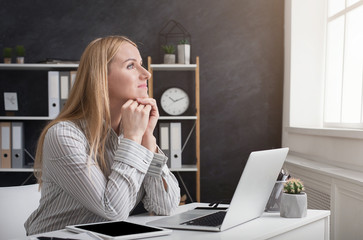 Thoughtful businesswoman working on laptop at office