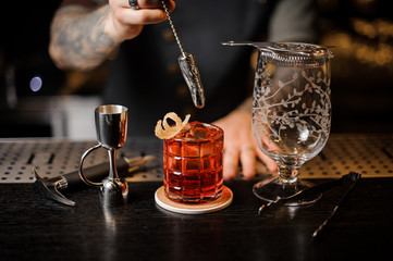 Bartender stirring a fresh red cocktail with a spoon