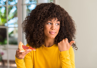 African american woman ready to eat pepperoni pizza slice pointing with hand and finger up with happy face smiling