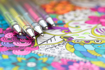 Adult coloring book, new stress relieving trend. Art therapy, mental health, creativity and mindfulness concept. Adult coloring page with pastel colored gel pen close up. © andreaobzerova