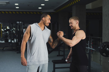 Muscular men shaking hands at gym