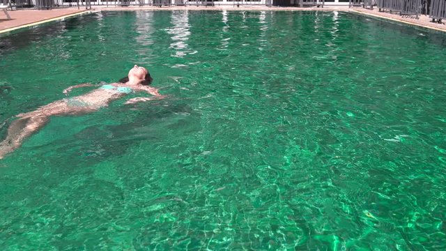 Woman swims backstroke in the outdoor pool