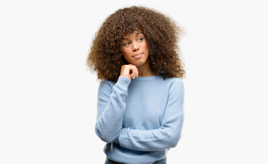 African american woman wearing a sweater with hand on chin thinking about question, pensive expression. Smiling with thoughtful face. Doubt concept.
